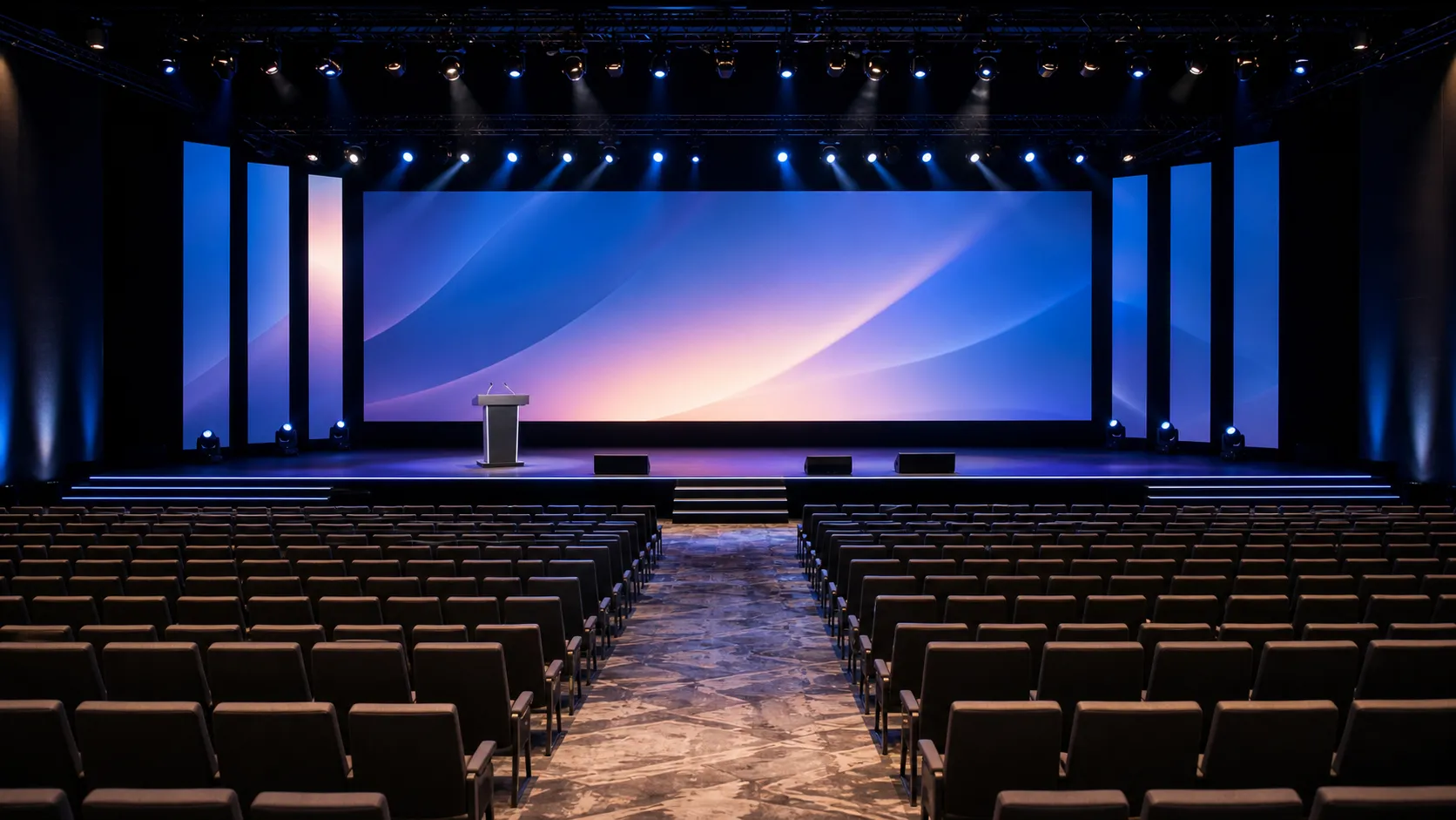 A keynote auditorium lit for a conference, raked seating toward a wide stage